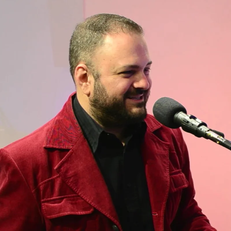 Brian on mic in a red jacket, mid-record.